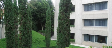 Un bâtiment moderne doté d’une cour intérieure agrémentée de haies soigneusement taillées et d’arbres hauts et élancés.
