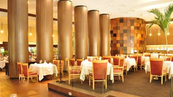 A restaurant with multiple tables and chairs, large cylindrical columns, and a checkered wall design.