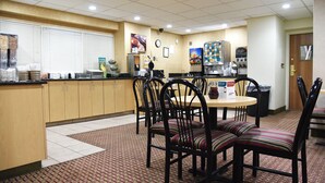 A clean, well-lit restaurant with a counter, chairs, and a clock on the wall. - Quality Inn & Suites Council Bluffs - Omaha East (Council Bluffs)