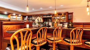 Zona de bar con sillas de madera y una barra.