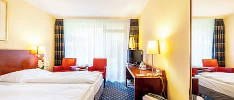 Una habitación de hotel con dos camas, un escritorio con lámpara, televisor y espejo.