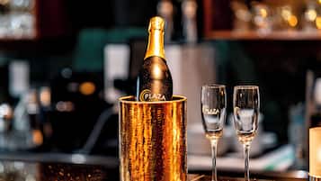 Eine Champagnerflasche in einem goldenen Behälter mit zwei Gläsern daneben.