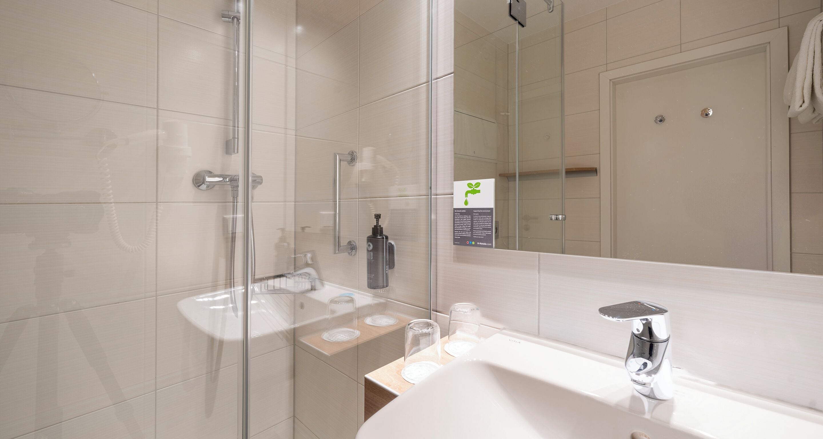 A modern bathroom with a glass shower enclosure, a white sink, and a large mirror.