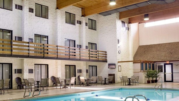 Una piscina interior con varias zonas de descanso, techo de madera y pared de piedra.