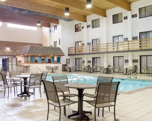 An indoor swimming pool area with multiple seating arrangements and a bar area.