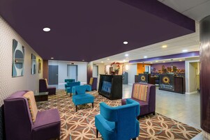 A lobby with purple walls, blue chairs, a reception desk, and a city view.