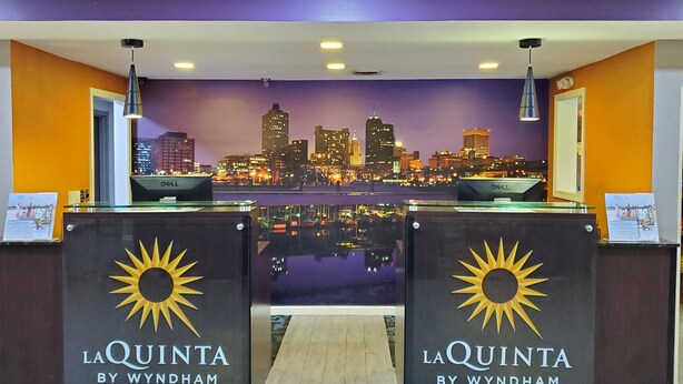 A hotel reception desk with a city skyline view in the background. - La Quinta Inn & Suites by Wyndham Memphis Airport Graceland (Memphis)