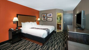 A hotel room with a bed, nightstand, lamp, TV, and a bathroom visible through an open door. - La Quinta Inn & Suites by Wyndham Memphis Airport Graceland (Memphis)