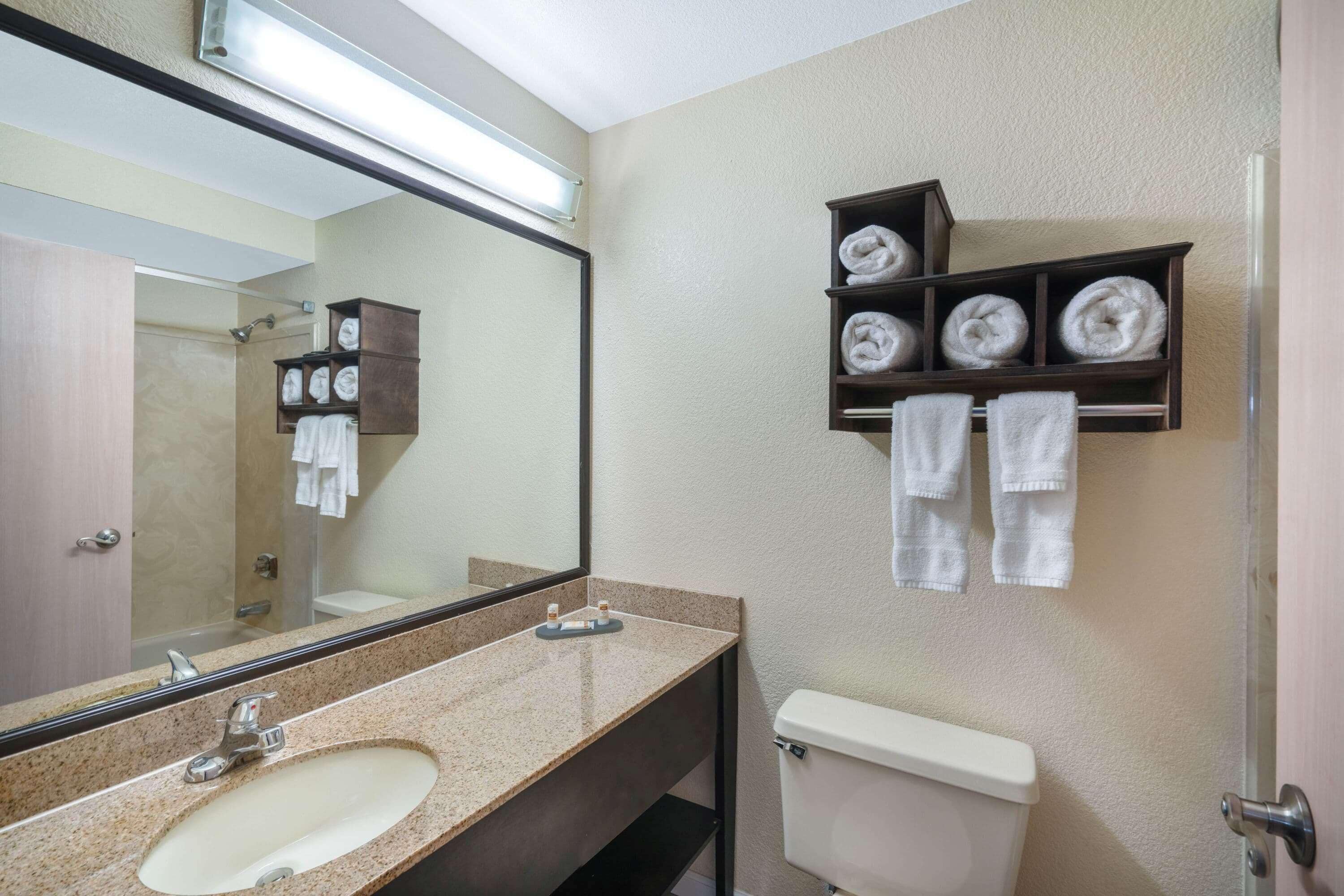 Une salle de bain équipée d’un lavabo, d’un miroir, de toilettes et d’un espace pour ranger les serviettes.