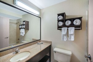 Un baño con lavamanos, espejo, inodoro y espacio para toallas.