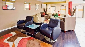 A hotel lobby with seating areas, a reception desk, and a large mirror on the wall. - La Quinta Inn & Suites by Wyndham Memphis Airport Graceland (Memphis)