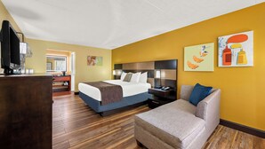 A hotel room with a bed, a sofa, a desk, and a TV.
