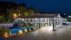 A hotel with a pool, outdoor seating, and a covered patio area.
