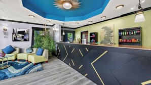 A modern bar area with a black and gold geometric design, a blue ceiling, and a green wall with a plant.