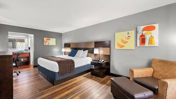 Una habitación de hotel moderna con una cama grande, un escritorio, una silla y obras de arte en las paredes.