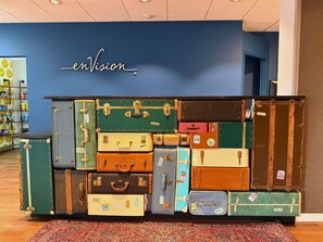 A wall display of vintage suitcases with a sign reading 'envision' above.