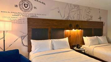 Habitación de hotel con dos camas, cabecero de madera, un mapa en la pared y una lámpara.