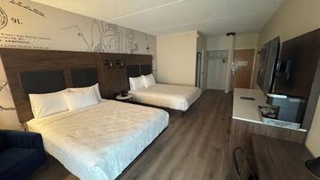 A hotel room with two beds, a small round table, a TV, and a wardrobe.