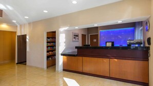 Un hall d’hôtel avec un comptoir d’accueil en bois, un mur éclairé en bleu et une horloge fixée au mur.