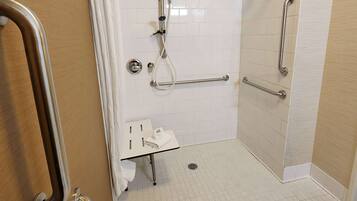 A bathroom with white tiled walls, a wooden door, a sink with a towel, and grab bars.