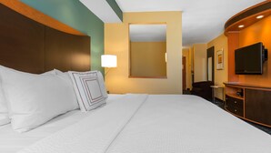 Une chambre d’hôtel avec un grand lit, un bureau doté d’un téléviseur à écran plat et un miroir au mur.