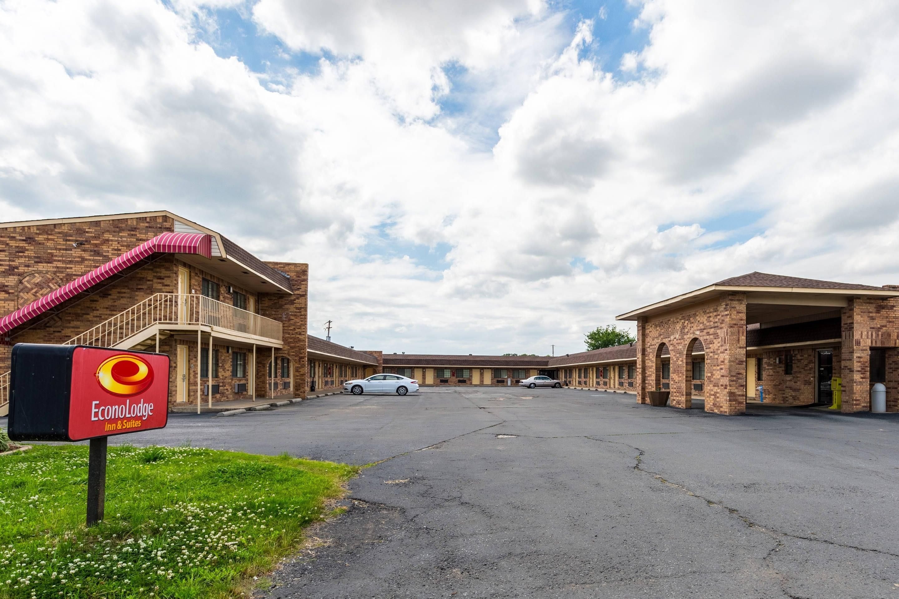 A motel with a brick facade, a covered parking area, and a sign for EconoLodge Inn & Suites.