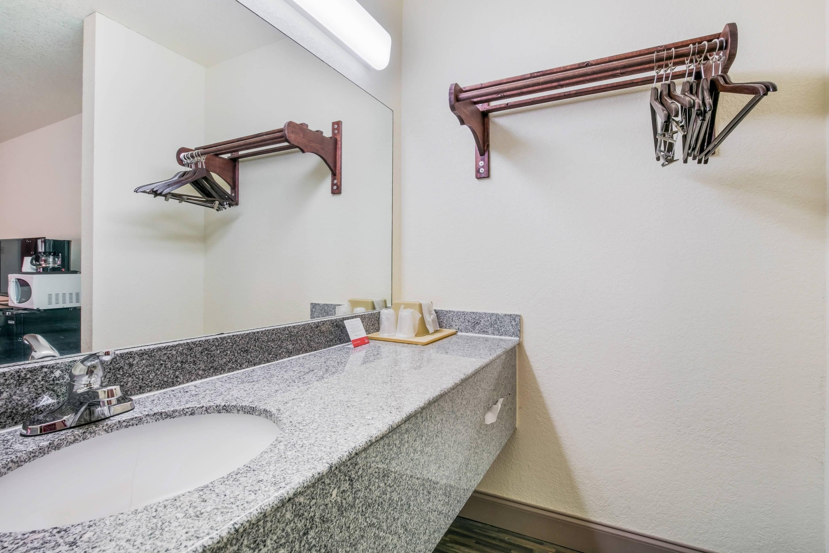A bathroom with a granite countertop sink, a mirror, and two towel racks.