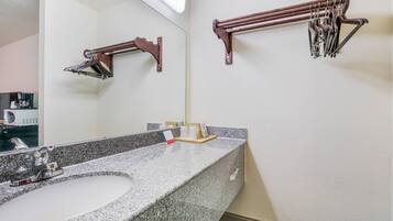 Een badkamer met een wastafel met granieten blad, een spiegel en twee handdoekrekken.