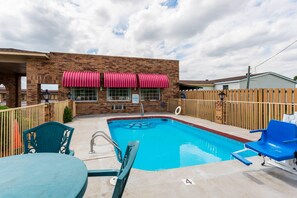 A swimming pool with a brick building in the background, a wooden fence, and outdoor seating. - Econo Lodge & Suites Brinkley (Brinkley)