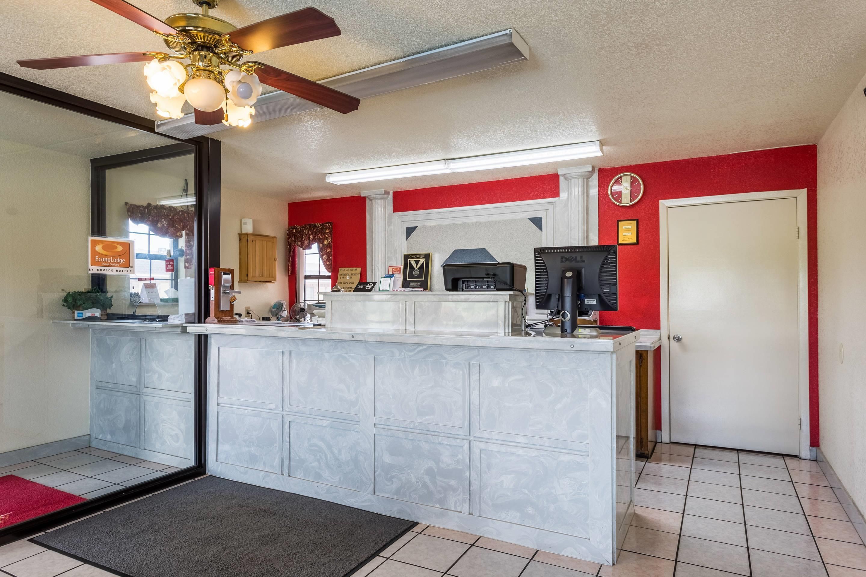 A hotel lobby with a reception desk, a clock, and a door.