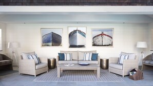 Un salon moderne comprenant un canapé, une table basse et trois tableaux encadrés sur le thème de la marine, accrochés au mur.