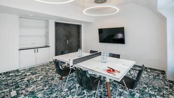 A modern conference room with a white table, black chairs, and a large screen.