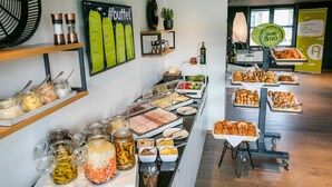 Zona de buffet con diversas opciones de comida, incluyendo carnes, quesos y productos de pastelería.