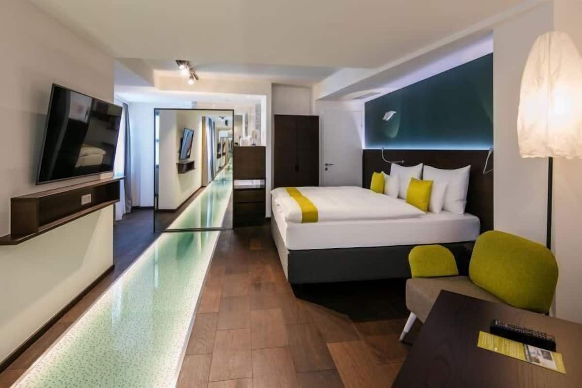 A hotel room with a bed, a TV, a desk, and a chair.