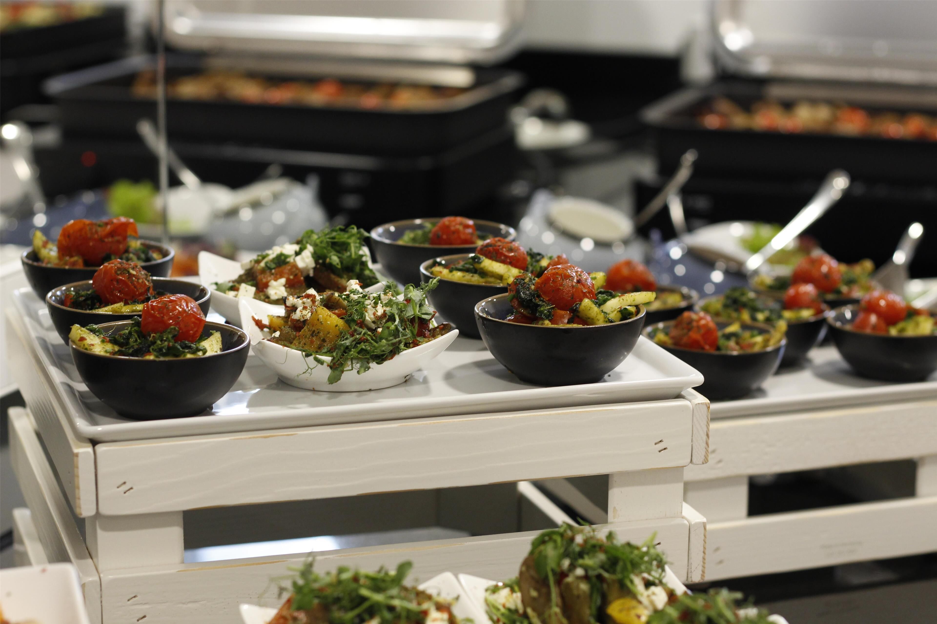 A buffet table with various dishes, including salads and vegetables.
