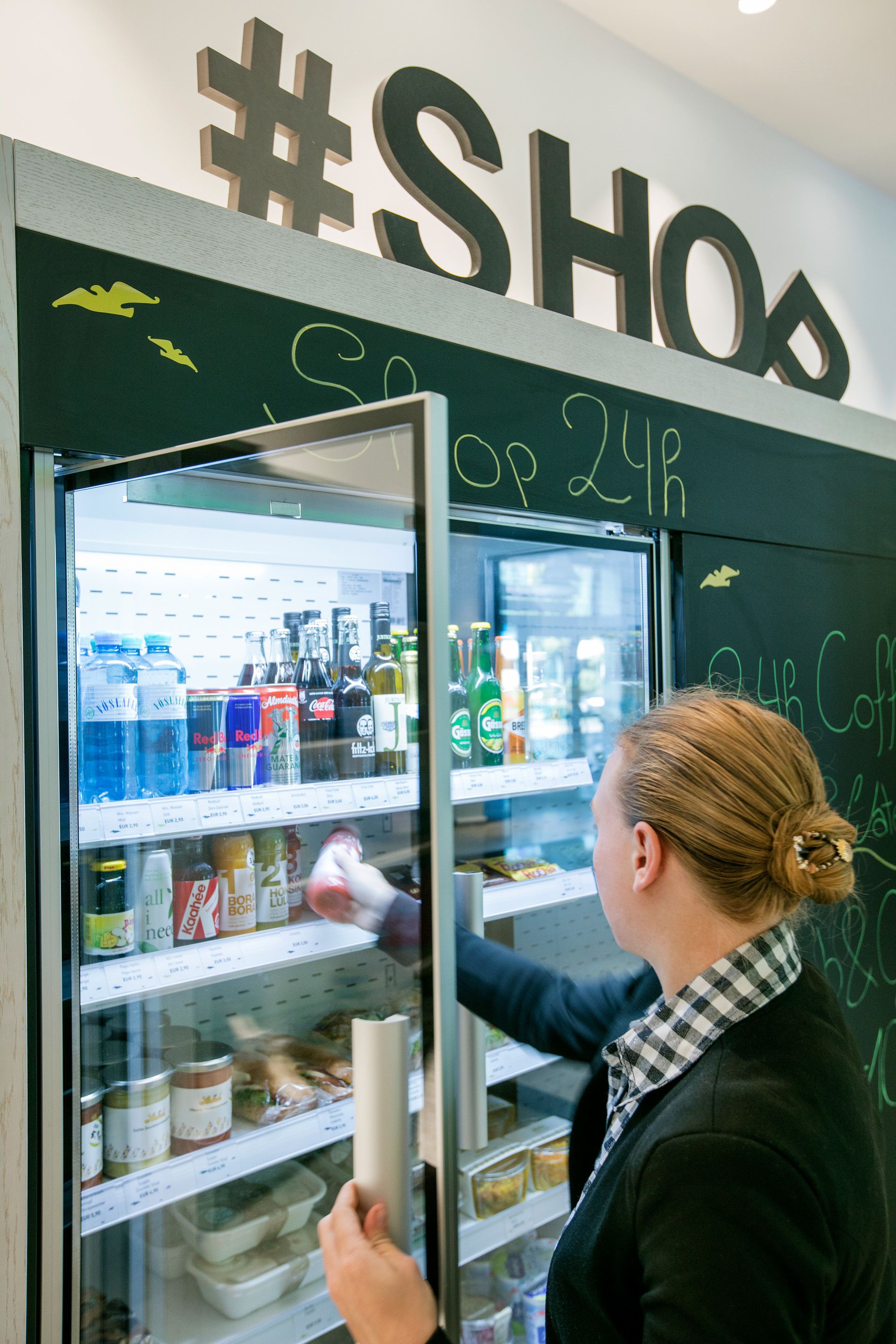Una persona abasteciendo una vitrina refrigerada en una tienda.