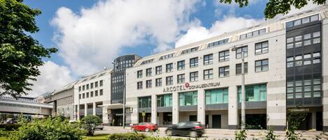 A modern building with multiple floors, large windows, and a sign reading "ARCOTEL DONAUZENTRUM".