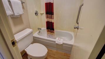 A small bathroom with a toilet, a bathtub, and a shower curtain.
