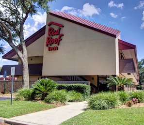 Un Red Roof Inn con techo rojo, paredes beige y entrada pavimentada.