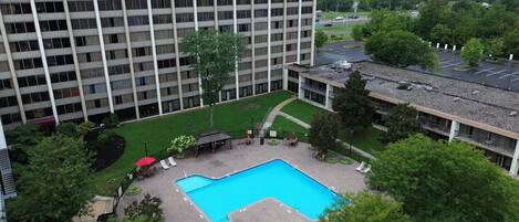Un edificio de gran altura con un patio que cuenta con una piscina, asientos al aire libre y un pequeño jardín.