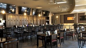 Un restaurante con barra, varias mesas y sillas, y una decoración interior moderna.