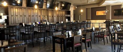 Un restaurante con barra, varias mesas y sillas, y una decoración interior moderna.
