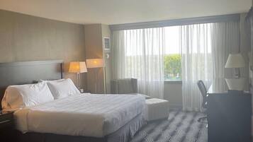 Una habitación de hotel con una cama grande, dos mesitas de noche, un escritorio y una silla.