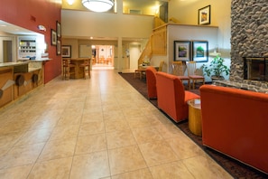 A hotel lobby with a reception desk, seating area with chairs, a staircase, and a stone fireplace. - Holiday Inn Express Grants Pass by IHG (Grants Pass)
