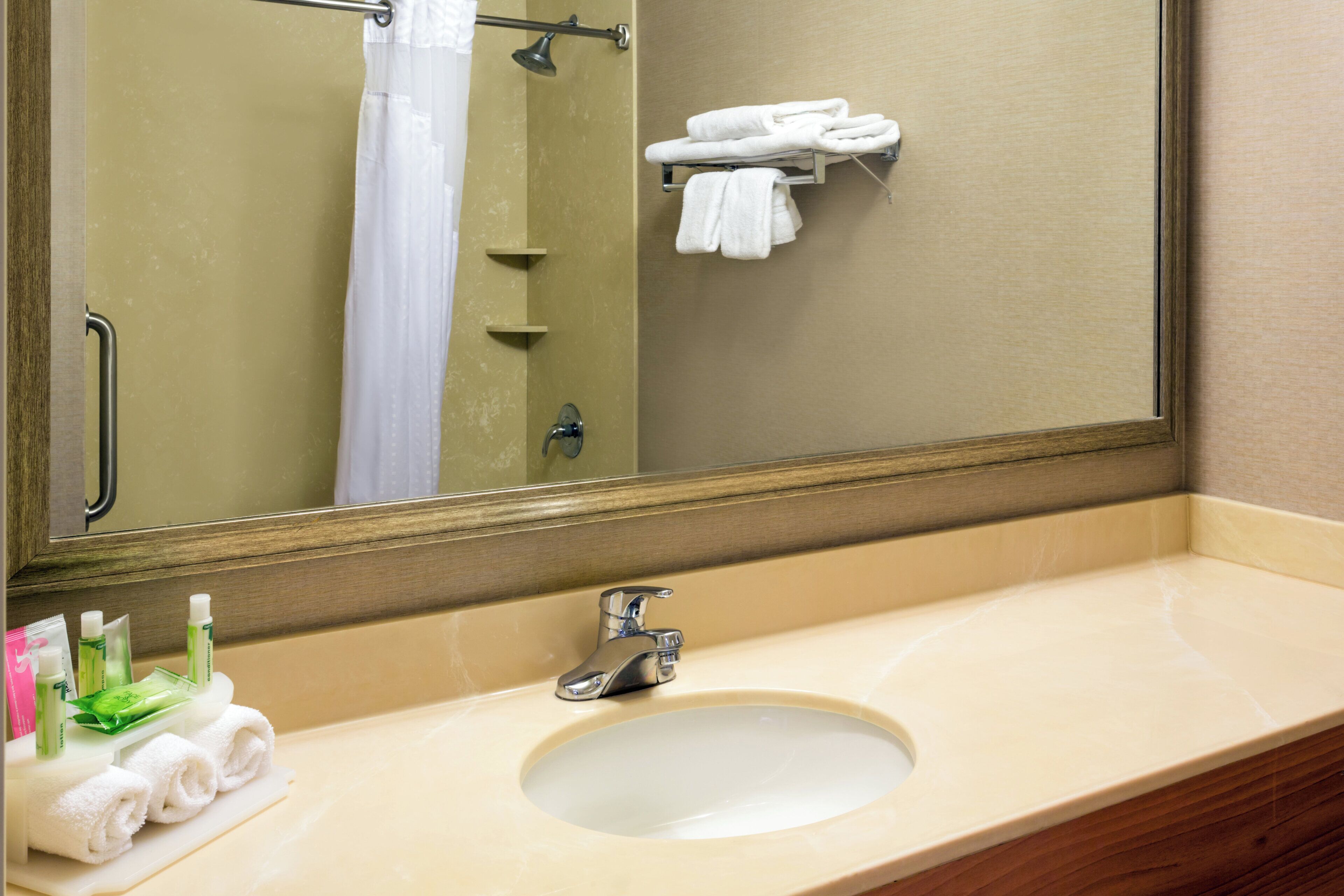 Un baño con lavamanos, espejo y perchero para toallas.