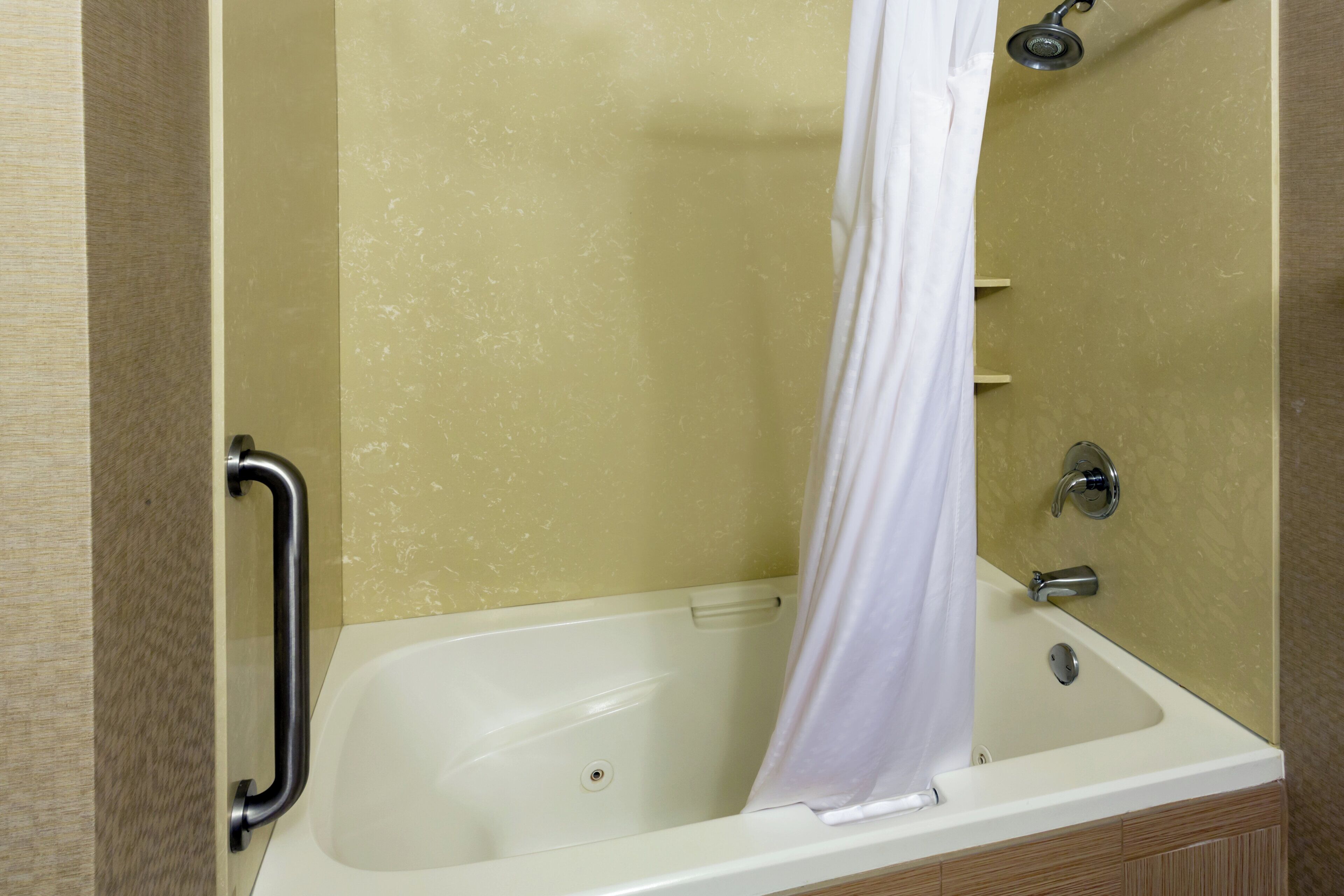 A bathtub with a shower curtain, a grab bar, and a faucet.