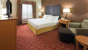 A hotel room with a large bed, a desk, a chair, a lamp, and a television.