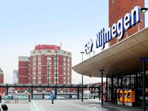 A hotel with a prominent sign, a covered entrance, and a parking area with vehicles.