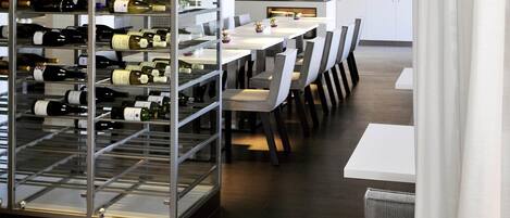 A modern dining area with a wine rack, tables, and chairs.