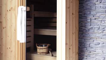 An open sauna with wooden benches and a stone wall.